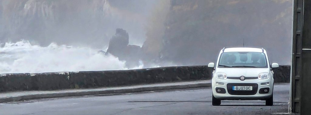 Coastal road on Terceira Island with waves crashing against volcanic cliffs – Drive Terceira scenic drive.