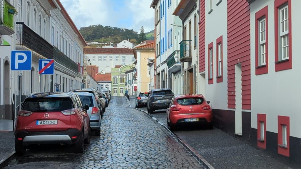 Historic cobblestone street in Angra do Heroísmo with colorful Portuguese architecture.